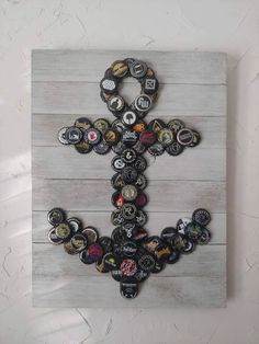 a cross made out of bottle caps is mounted on a wooden board with white paint