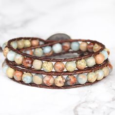 Genuine leather and beautiful Jasper stones that will remind you of a sunny beach, make up this gorgeous double wrap bracelet. Sand, dreamy light blue, and hints of rust swirl around in these stones and contrast nicely against a bold brown leather. 6mm (.62") diameter Aqua Terra Jasper gemstones Oval silver button, about 19mm (3/4") in width Rust brown leather Signature Bluefish logo heart charm 34 - 39 cm/13.5 - 15.5" length 2 button loop adjustments to fit most wrists Logo Heart, Beaded Leather Wraps, Aqua Terra, Double Wrap Bracelet, Silver Button, Sunny Beach, Silver Buttons, Bead Leather, Jasper Stone