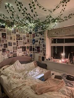 an unmade bed in a messy room with pictures on the wall and lights hanging from the ceiling