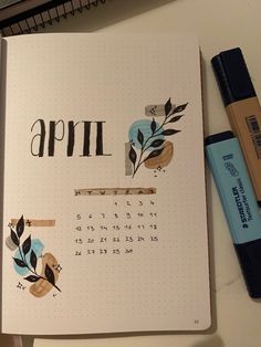 an open notebook with the word april written on it next to a marker and pen