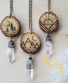 three necklaces with wood slices and glass beads hanging from chains on a white surface