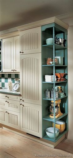 a kitchen with green cabinets and white cupboards in the corner, filled with dishes