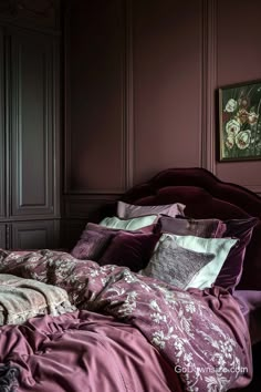 a bed with purple comforter and pillows in a dark room next to a painting on the wall