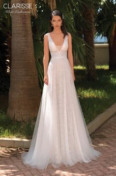 a woman in a white wedding dress standing on a brick walkway with palm trees behind her