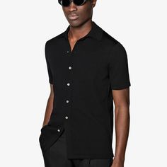 A perfect way to elevate any casual look, this black short-sleeve polo cardigan features a classic polo collar, a seven-button closure, and a slim, tapered silhouette for a sleek aesthetic. Black Polo Shirt With Placket, Black Polo Collar Sweater For Work, Modern Black Polo Shirt With Collared Neckline, Black Short Sleeve Polo Sweater For Work, Black Polo Shirt With Button Closure, Black Polo Shirt With Seamless Collar For Work, Modern Semi-formal Tops With Short Sleeves, Modern Semi-formal Short Sleeve Tops, Classic Black Polo Shirt With Collared Neckline