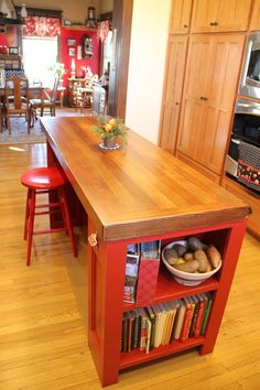 a kitchen island with bookshelves and bowls of food on the counter, in front of an oven