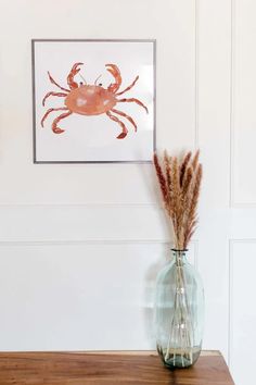 there is a vase with some flowers in it and a crab painting on the wall