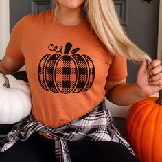 Hey there, autumn enthusiast! Ready to blend cozy comfort with a touch of seasonal style? The Plaid Pumpkin Bella Graphic Tee is perfect for celebrating fall with a classic twist. Whether you're browsing a farmers' market, sipping on a pumpkin spice latte, or enjoying a crisp fall day, this tee brings a stylish and festive flair to your autumn wardrobe. Crafted from ultra-soft, high-quality Bella canvas, the Plaid Pumpkin Graphic Tee offers exceptional comfort and durability. Its relaxed fit and premium fabric keep you cozy and looking effortlessly stylish as you enjoy all the best of fall. Featuring a charming plaid pumpkin design, this tee combines the warm, familiar pattern of plaid with the vibrant appeal of autumn pumpkins. The blend of classic plaid and pumpkin graphics creates a fes Casual Burnt Orange Tops For Fall, Burnt Orange Casual Tops For Fall, Orange Crew Neck T-shirt For Fall, Orange Crew Neck Top For Fall, Orange Long Sleeve T-shirt For Fall, Orange Cotton Top For Fall, Orange Cotton Tops For Fall, Plaid Pumpkin, Pumpkin Graphic