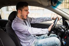 a man sitting in the driver's seat of a car with his hand on the steering wheel