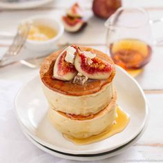 stack of pancakes topped with fruit and butter