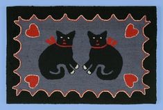 two black cats sitting on top of a rug with red hearts in the middle,