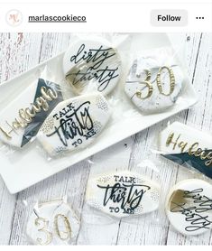 some cookies are on a white plate and one is decorated with gold foil lettering that says happy 30th