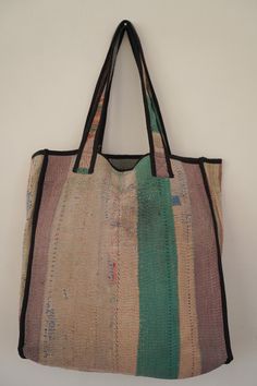 a large multicolored bag hanging on a white wall with black straps and handles