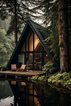 a small cabin sits on the edge of a body of water in front of some trees