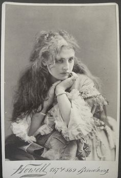 an old black and white photo of a young woman with curly hair wearing a dress