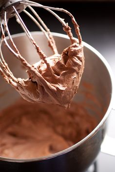 a whisk is being used to make chocolate frosting in a mixing bowl