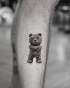 a black and white photo of a small teddy bear tattoo