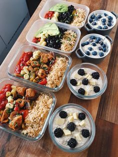 six plastic containers filled with food on top of a wooden table next to bowls of fruit and vegetables