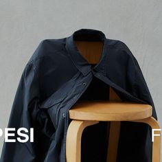 a wooden chair sitting next to a black jacket on top of a white background with the words pesi written below it