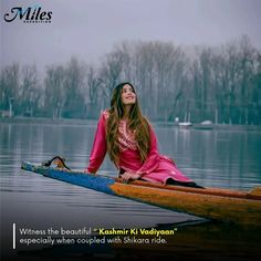 a woman sitting on top of a wooden boat in the middle of a body of water