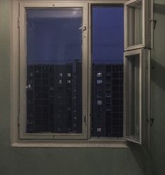 an open window with the night sky seen through it's panes in front of a cityscape