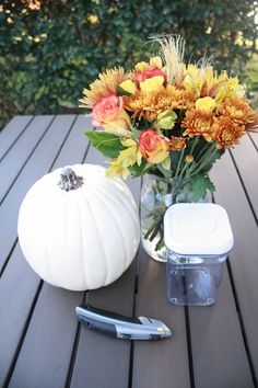 a vase filled with flowers sitting on top of a wooden table next to a knife