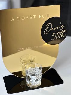 a toast for dinner's 50th with two shot glasses on the table next to it