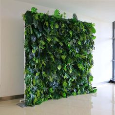 a living wall made out of plants and leaves in an office space with white tile flooring