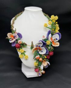 a white mannequin with colorful flowers and leaves on it's neckline