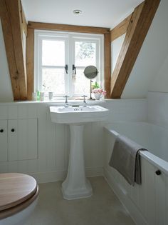 a white pedestal sink sitting under a window next to a toilet and bathtub in a bathroom