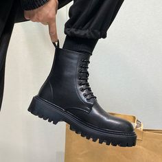 a person wearing black boots is holding a brown bag