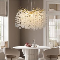 a chandelier hanging over a white table in a room with chairs and windows