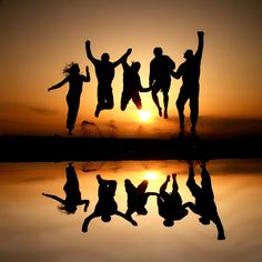 four people jumping in the air at sunset