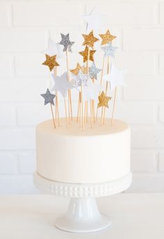 a white cake topped with stars on top of a wooden table next to a brick wall