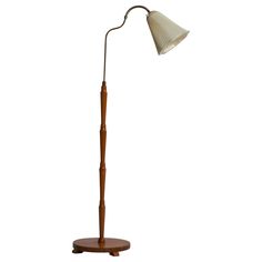 a wooden floor lamp with a white shade on it's head and an oval base