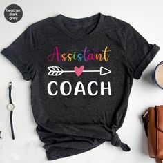 "Assistant Coach Shirt, Coach T-shirt, Sports Coach Apparel, Baseball Coach Gift, Cute Coach T-shirt, Instructional Coach Shirt * Unisex T Shirt: \"Bella Canvas\" - Retail fit, Runs true to size. - Solid colors: 100% Ring-Spun soft cotton. Heather colors: 52% Ring-Spun cotton 48% polyester. * V-Neck T Shirt: \"Bella Canvas\" - Retail fit, Runs true to size. - Solid colors: 100% Ring-Spun soft cotton. * Women's T Shirt: \"Anvil\"  Feminine cut, Runs smaller than usual (Please use the size chart). - 100% Ring-Spun soft cotton. - Color \"Dark Grey\" is: \"Heavy Metal\". And color \"Athletic Heather\" is: \"Grey Heather\" in Women's shirts.                                                                                                   * Unisex T Shirt: \"Gildan Softstyle\" - Runs true to siz Casual Gray T-shirt With Name Print, Multicolor Team Name Short Sleeve Top, Casual Multicolor T-shirt With Team Name, Multicolor Short Sleeve Top With Team Name, Gray Graphic Tee With Name Print, Gray Custom Print Graphic Tee, Multicolor Crew Neck T-shirt With Name Print, Gray Short Sleeve Top With Team Name, Gray Crew Neck T-shirt With Name Print