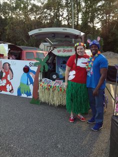 two people standing in front of a food truck with grass skirts on it's sides