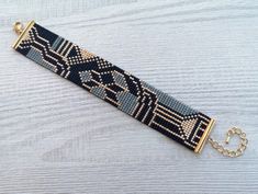 a beaded bracelet on a wooden surface with a gold chain hanging from the clasp