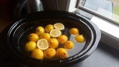 some lemons are in a black bowl on a windowsill