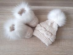 three white knitted hats and booties on a wooden floor