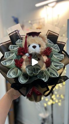 a teddy bear with money in it's bouquet is being held up by someone