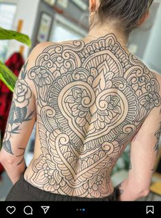 the back of a woman's body with intricate tattoos on her upper and lower back