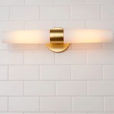 a bathroom light that is on the side of a white brick wall in a public restroom