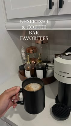 a person is holding a coffee mug in front of a coffee maker and espresso machine