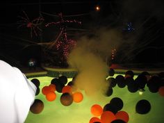 a hot tub filled with lots of oranges and black balls in the water at night