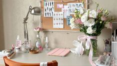 a desk with flowers in a vase and other office supplies on the table next to it