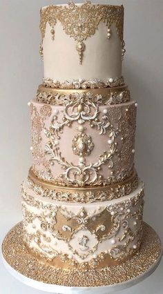 a three tiered cake with gold and white decorations