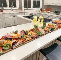 a large number sign sitting on top of a kitchen counter covered in fruit and veggies