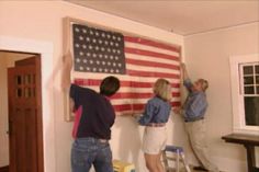 three people painting the american flag on a wall