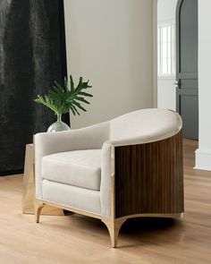 a white chair sitting on top of a wooden floor next to a potted plant